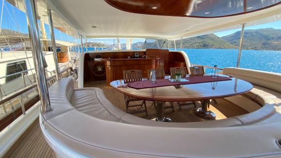 An elegant deck of the Gulet Sahinoğlu, equipped with a large dining table and comfortable seating.